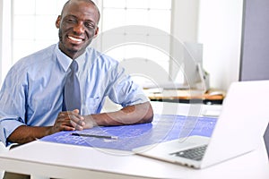 African american architect working with computer and blueprints in office