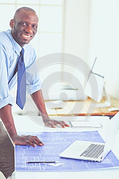 African american architect working with computer and blueprints in office