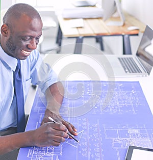 African american architect working with computer and blueprints in office