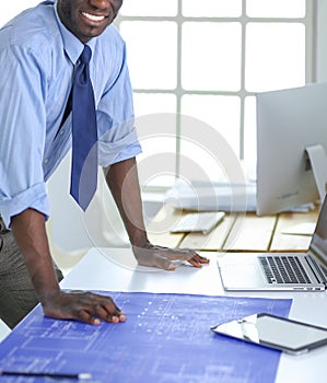 African american architect working with computer and blueprints in office