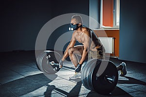 African american athletic man waiting and preparing before lifting heavy barbell. fitness, sport, training, gym concept. deadlift