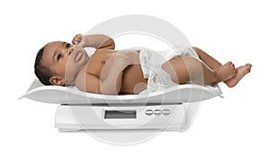 African-American baby lying on scales against white