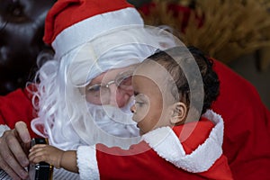 African American baby is opening the christmas present with Santa claus at night for season celebration