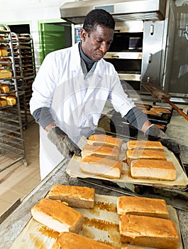 African-american baker spreads freshly baked bread on a pallet