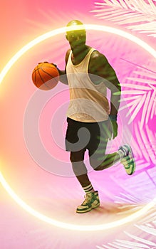 African american basketball player dribbling ball and running by circle and plants