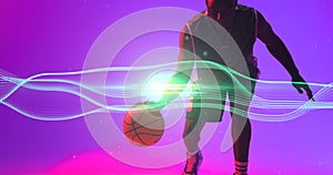 African american basketball player dribbling ball by wave patterned lines and lens flare