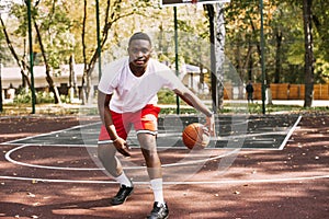 African American basketball player on an outdoor sports ground playing with a ball. doing sports on the street