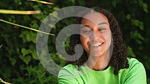 African American biracial teen girl teenager young woman turning to camera then smiling, laughing and happy wearing a green t-shir