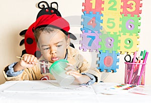 African American black boy drawing with colorful pencils in preschool in kindergarten