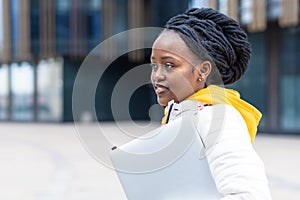 African american black female girl student with creative hair is remote studing, working, using laptop outdoor. back to school.