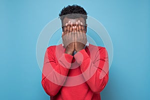 African american black man covering eyes being stressed trying to stay anonym.