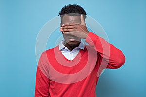 African american black man covering eyes being stressed trying to stay anonym.