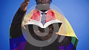 African american black man with elegant suit rainbow flag covering his shoulders holding holy bible in the hands. Gay