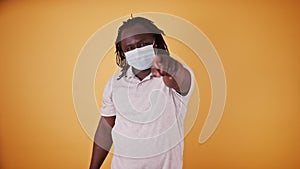 African american black man with medical mask and braidd hair pointing finget towards the camera