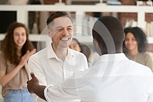 Black boss handshake congratulating excited Caucasian employee photo