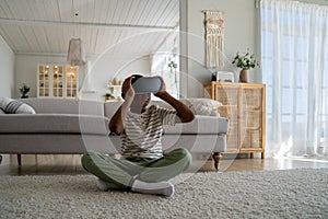 African American boy child sitting on floor at home using virtual reality device watching 3d video