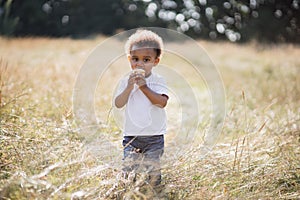African american boy eating cupcake while standing on field
