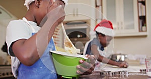 African american boy and girl wearing aprons baking together in the kitchen at home