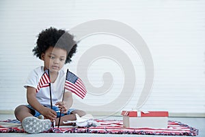 African American boy holding little usa flags sitting on the floor