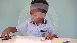African American boy learning how to draw with crayon on table