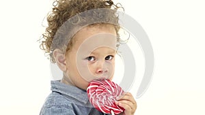 African american boy licks a candy. White background. Slow motion. Close up