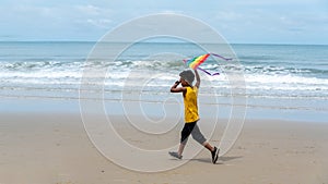 African American boy play flying kite toy at tropical beach on summertime