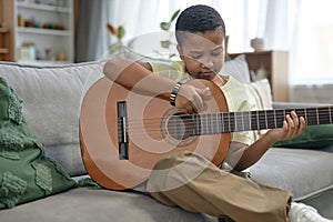 African American boy playing guitar at home