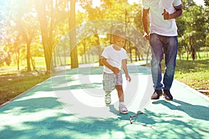 African American boy walking and playing with dad in green park