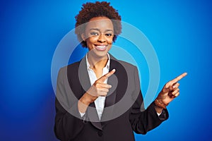 African american business executive woman over  blue background smiling and looking at the camera pointing with two hands