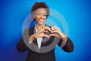 African american business executive woman over  blue background smiling in love showing heart symbol and shape with hands