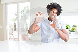 African American business man afraid and terrified with fear expression stop gesture with hands, shouting in shock