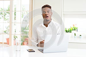 African american business man working using laptop afraid and shocked with surprise expression, fear and excited face