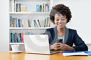 African american business trainee sending message with mobile phone