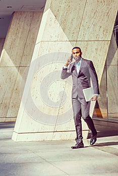 African American businessman talking on cell phone, walking out