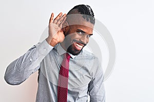 African american businessman with braids wearing tie standing over isolated white background smiling with hand over ear listening