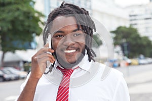 African american businessman with dreadlocks at phone in the city