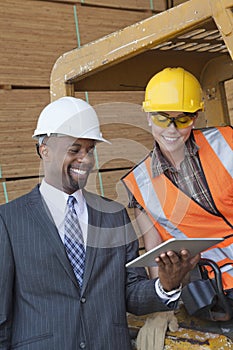 African American businessman and female industrial worker looking at tablet PC