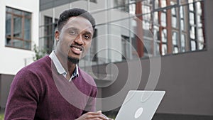 African american businessman giving a thumb up to camera, while using laptop.