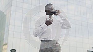 African American Businessman in glasses talking on cell phone, standing near his office