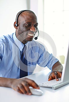 African american businessman on headset working on his laptop