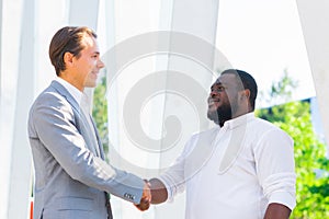 African-American businessman and his colleague in front of modern office building. Financial investors are talking