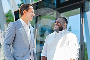 African-American businessman and his colleague in front of modern office building. Financial investors are talking