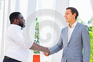 African-American businessman and his colleague in front of modern office building. Financial investors are talking