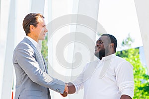 African-American businessman and his colleague in front of modern office building. Financial investors are talking