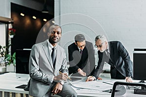 african american businessman looking at camera while business colleagues discussing work