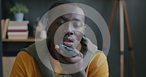 African American businessman recording audio messages and listening to voice in smartphone at work in office