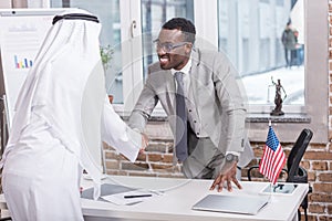 African american businessman shaking hands with arabic partner