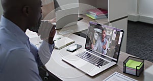 African american businessman sitting at desk using laptop having video call with male colleague