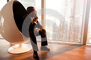 African-american businessman sitting in egg chair enjoying sunse