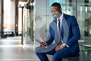 African american businessman smiling cheerful, using cell phone at office building, internet, broadband, 5G, copy space photo